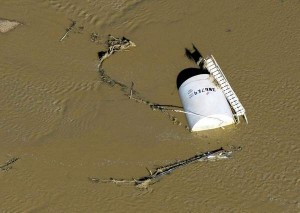 A crude oil storage tank lies on its side in floodwater after the recent floods in Colorado. John Wark/Associated Press